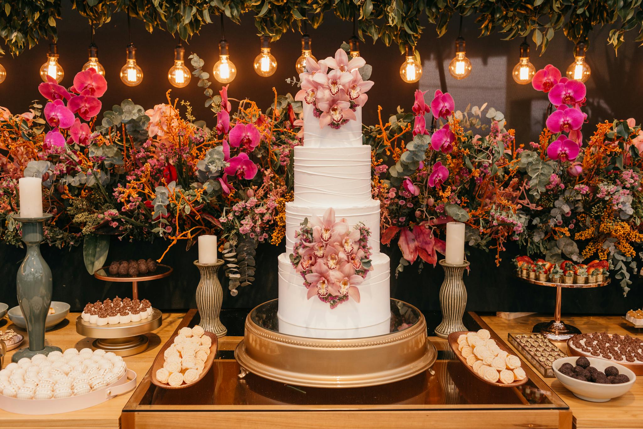 A beautifully decorated wedding cake surrounded by colorful flowers and sweet treats, perfect for a festive celebration.