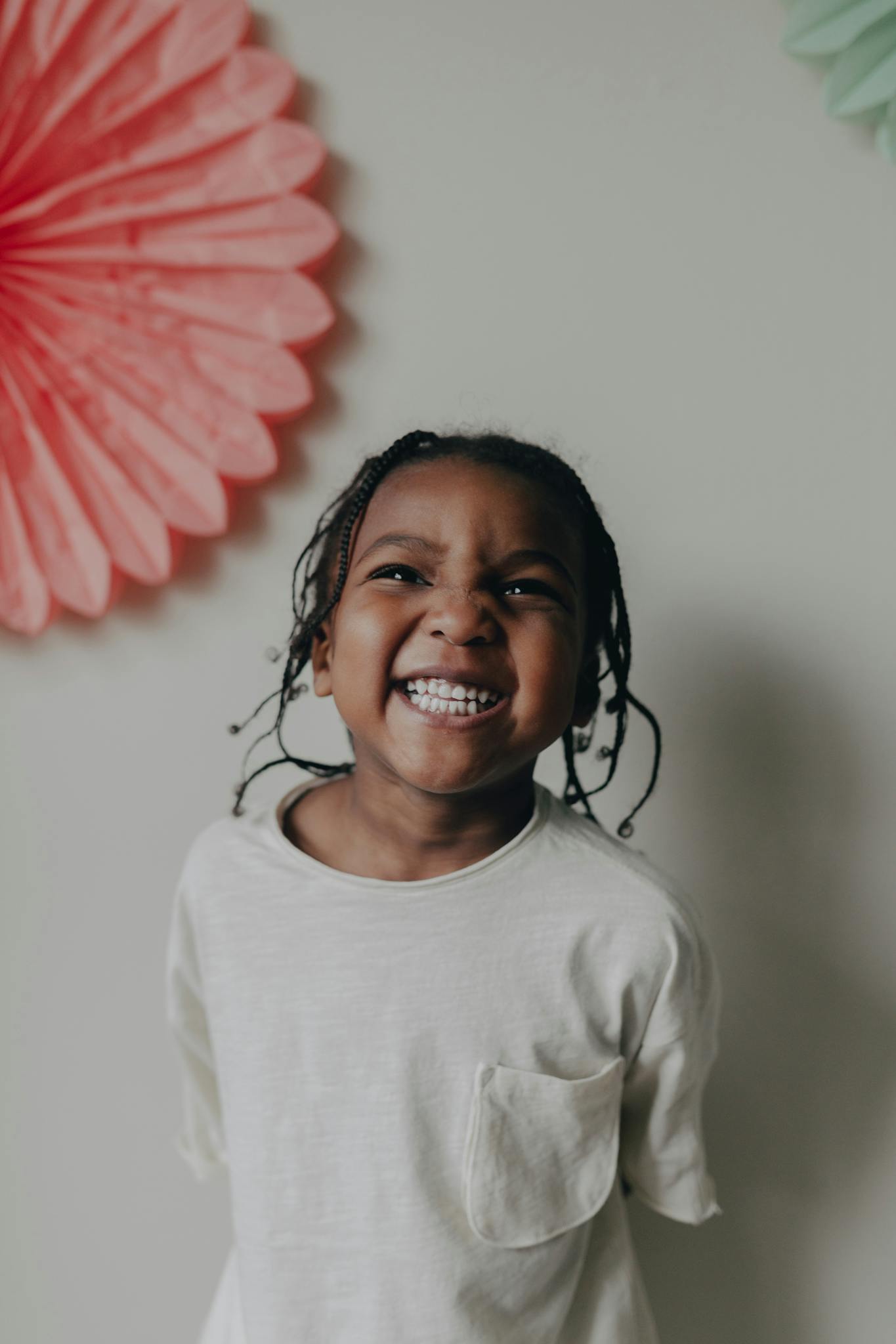 A young girl smiles brightly next to colorful decorations, capturing a joyful moment indoors.